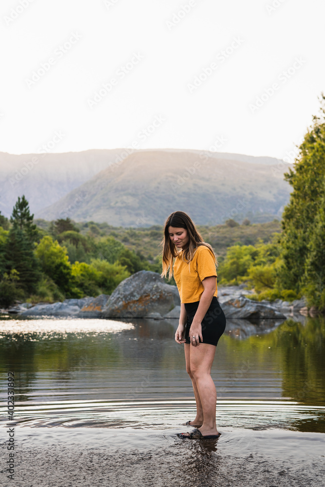 girl dressed in yellow enjoying and playing on a bridge near a river with a background of mountains