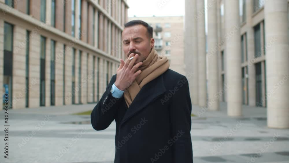 Handsome businessman smoking cigarette on urban street Handsome businessman smoking cigarette on urban street