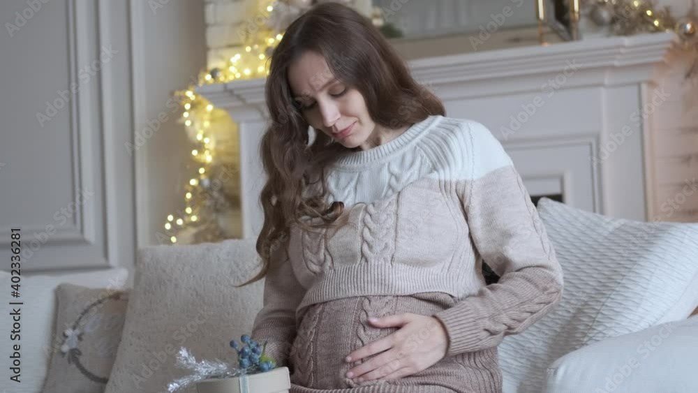 beautiful pregnant woman with a gift on the sofa beautiful pregnant woman with a gift on the sofa