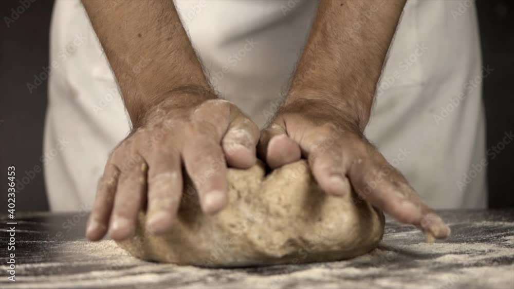 Close up of a baker´s hands Kneading Sourdough Bread Dough wearing a white apron in slow motion Close up of a baker´s hands Kneading Sourdough Bread Dough wearing a white apron in slow motion