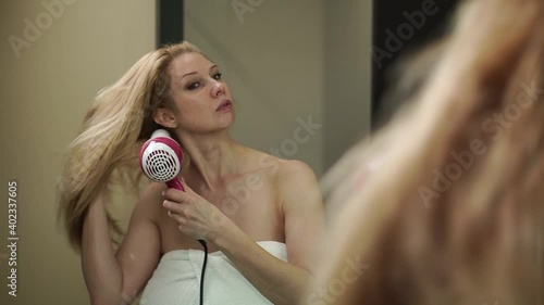 Woman washing hair behind glass of shower stall