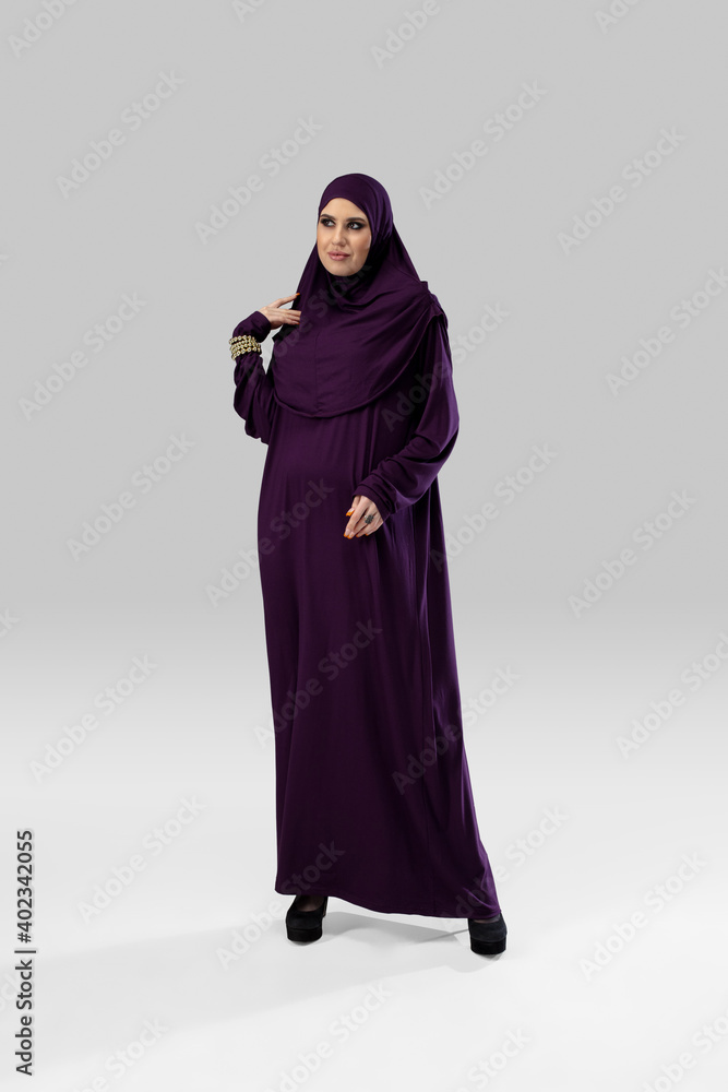 Purple. Beautiful arab woman posing in stylish hijab isolated on studio background with copyspace for ad. Fashion, beauty, style concept. Female model with trendy make up, manicure and accessories.