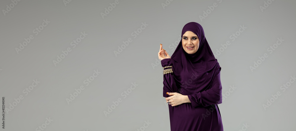 Flyer. Beautiful arab woman posing in stylish hijab isolated on studio background with copyspace for ad. Fashion, beauty, style concept. Female model with trendy make up, manicure and accessories. Flyer. Beautiful arab woman posing in stylish hijab isolated on studio background with copyspace for ad. Fashion, beauty, style concept. Female model with trendy make up, manicure and accessories.
