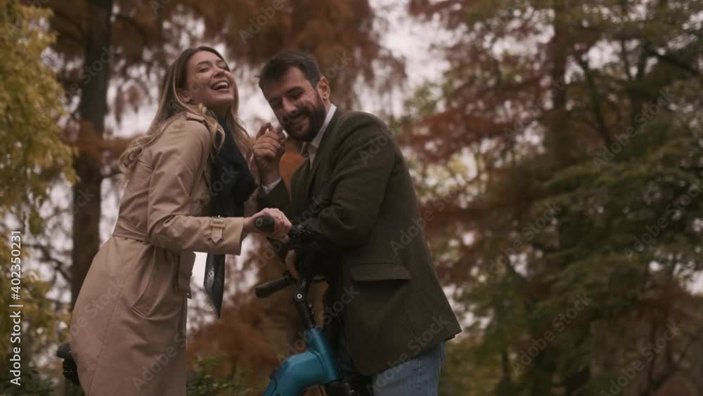 Handsome young couple in the autumn park with electrical bicycle Handsome young couple in the autumn park with electrical bicycle