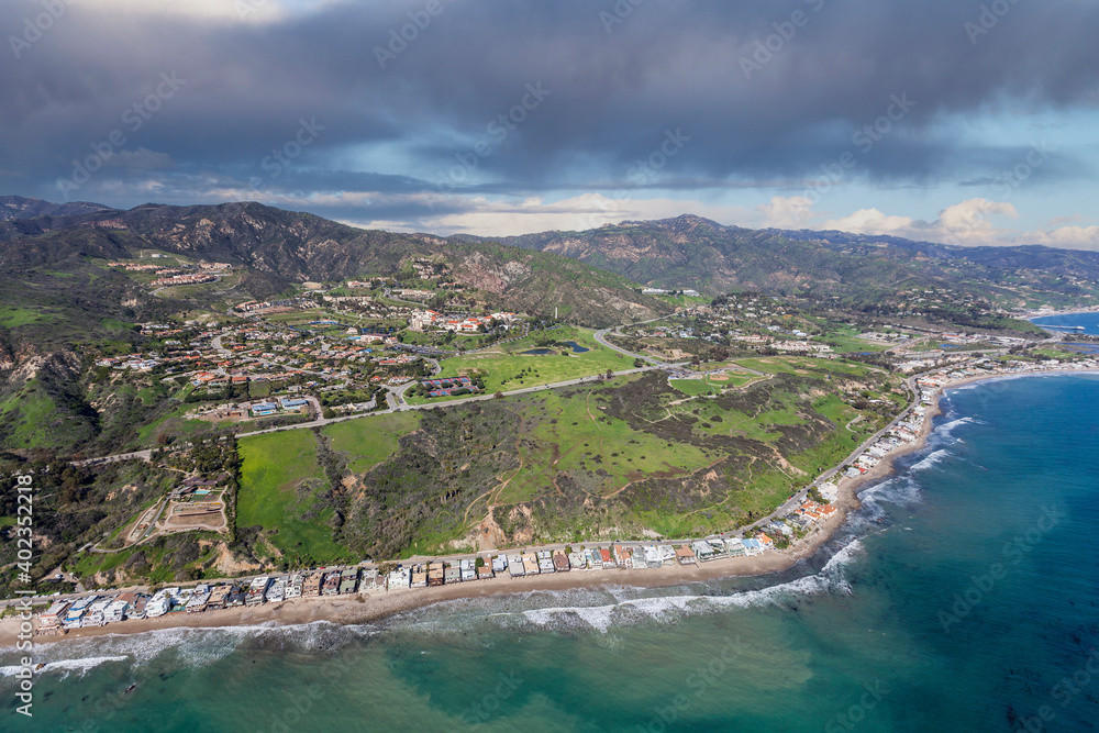Aerial view of Malibu California pacific ocean shoreline homes, bluffs and beaches with stormy sky.