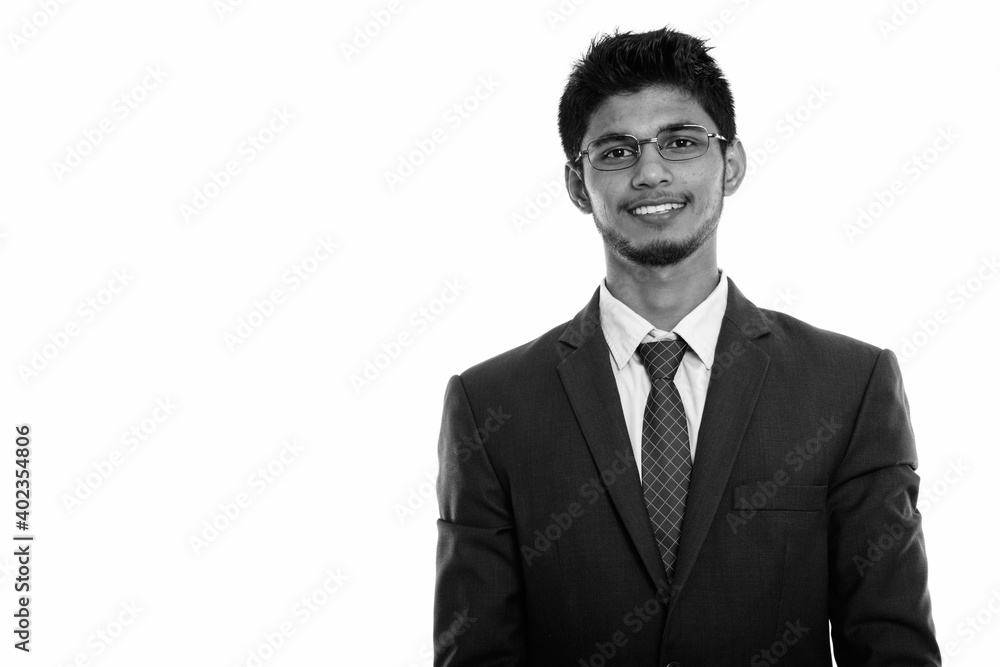 Studio shot of young happy Indian businessman smiling while wearing eyeglasses Studio shot of young happy Indian businessman smiling while wearing eyeglasses