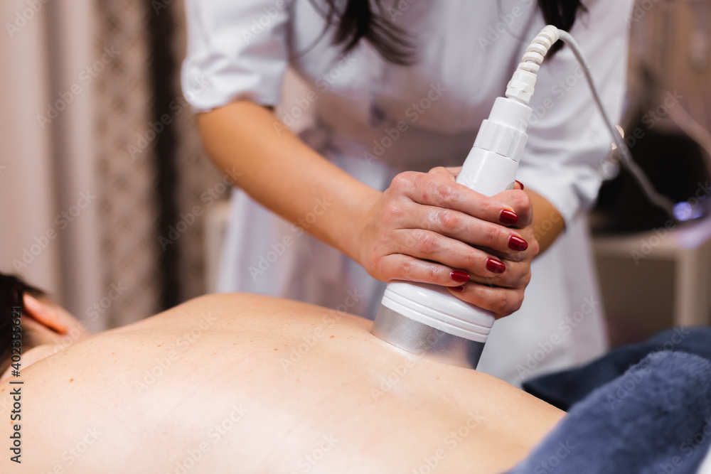 Fototapeta premium The girl in the spa salon receives a back and neck massage, lies in the cosmetology table, relaxed and enjoys the process
