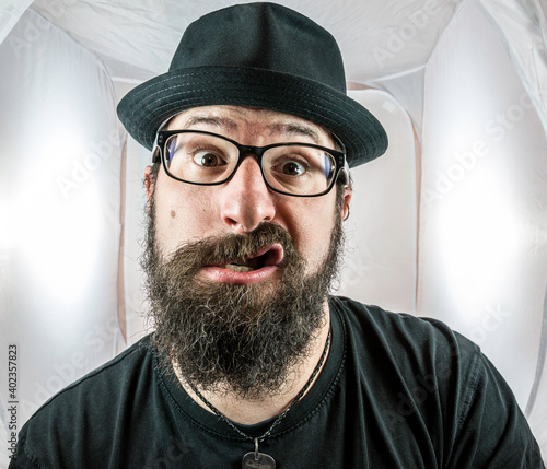 A silly looking bearded man with glasses and a black hat photo