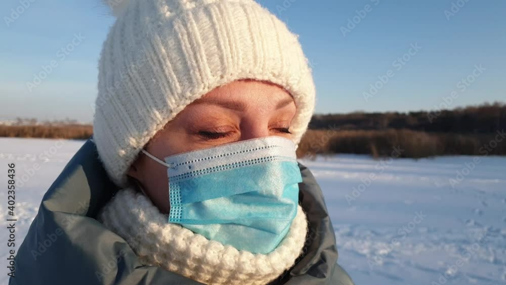 a beautiful woman in a medical mask walks in a winter park, wearing a medical mask in public places helps prevent the development of coronavirus epidemia a beautiful woman in a medical mask walks in a winter park, wearing a medical mask in public places helps prevent the development of coronavirus epidemia