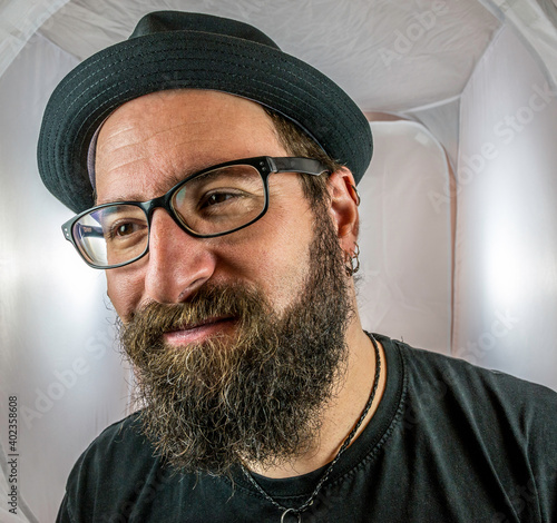 A bearded smiling man in a good mood with black glasses