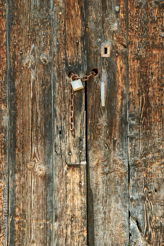 Old wooden door with chain and security lock Old wooden door with chain and security lock