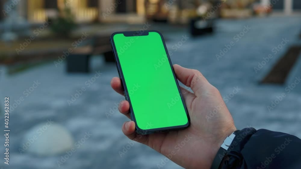 Shot of hands man use phone with vertical green screen stand on sunny street outdoors. Cellphone communication touchscreen tapping media. Slow motion Shot of hands man use phone with vertical green screen stand on sunny street outdoors. Cellphone communication touchscreen tapping media. Slow motion