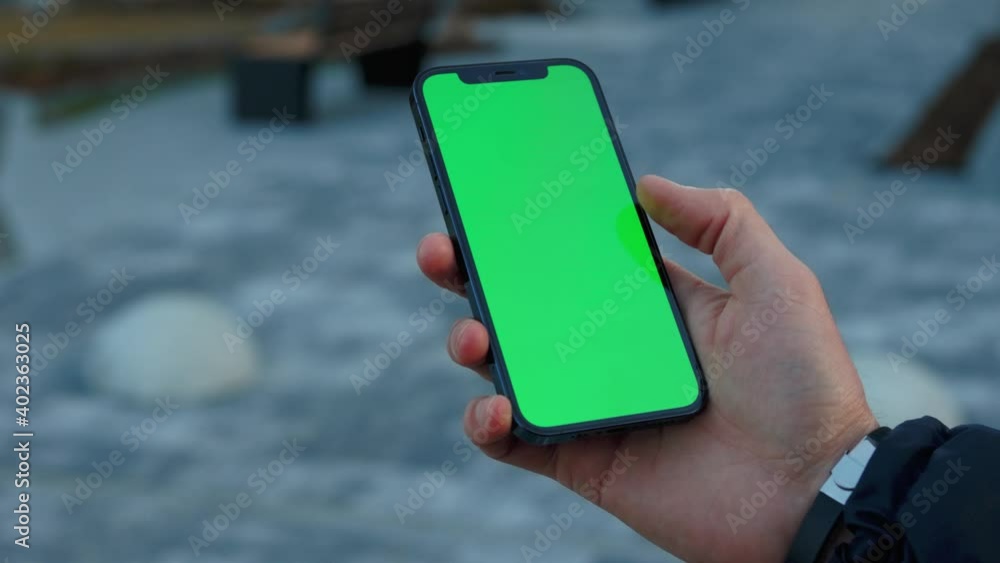 Close up hands man use phone with vertical green screen stand on sunny street outdoors. Cellphone communication touchscreen tapping media. Slow motion Close up hands man use phone with vertical green screen stand on sunny street outdoors. Cellphone communication touchscreen tapping media. Slow motion