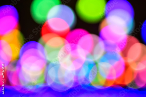 Multicolored holiday lights in defocus. Blurred abstract illuminate decorative lights with bokeh in night background.