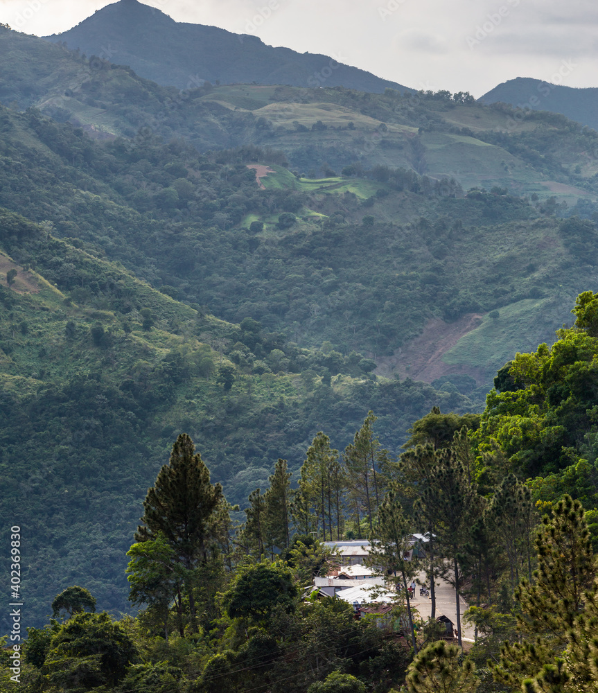 dramatic image of a small caribbean mountain village in the dominican republic with hills and trees in background.
