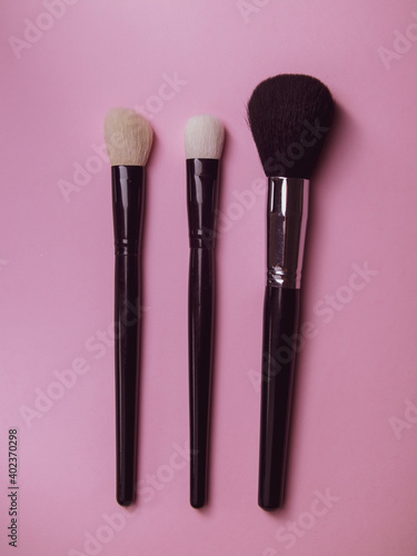 Fototapeta Naklejka Na Ścianę i Meble -  three makeup brushes on a pink background. professional brushes for mascara and powder. make-up