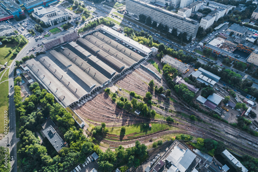 Railway station with a departing train at sunset in the summer in a big city. Aerial shot with a drone