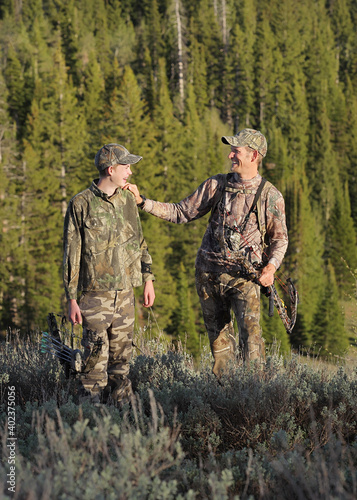 Canvas-taulu father and son bow hunting and interracting in woods full-length