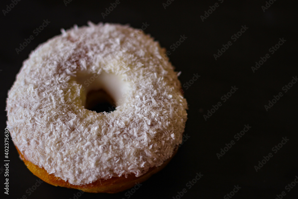 Delicious Donuts with coconut shavings on a black background Delicious Donuts with coconut shavings on a black background