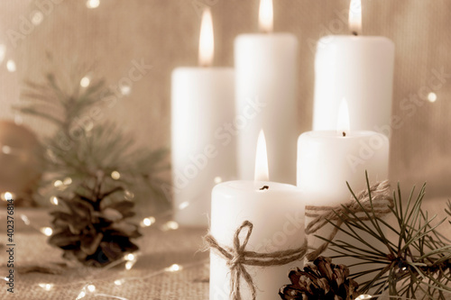 Burning candles on a natural beige background. Merry Christmas and Happy New Year. Greeting card. Close up. Copy space.