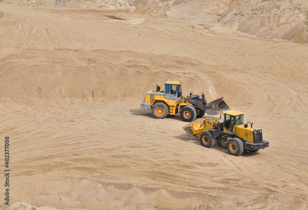 Obraz premium Wheel loader working at the sand open pit. Quarry in which sand and gravel is excavated from the ground. Mining industry.