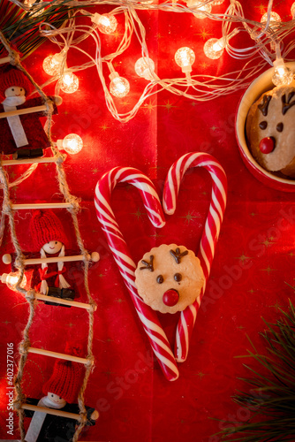 Postcard New Year's decor, gingerbread cookies New Year's deer, heart-shaped candies, lights, tree on a red background