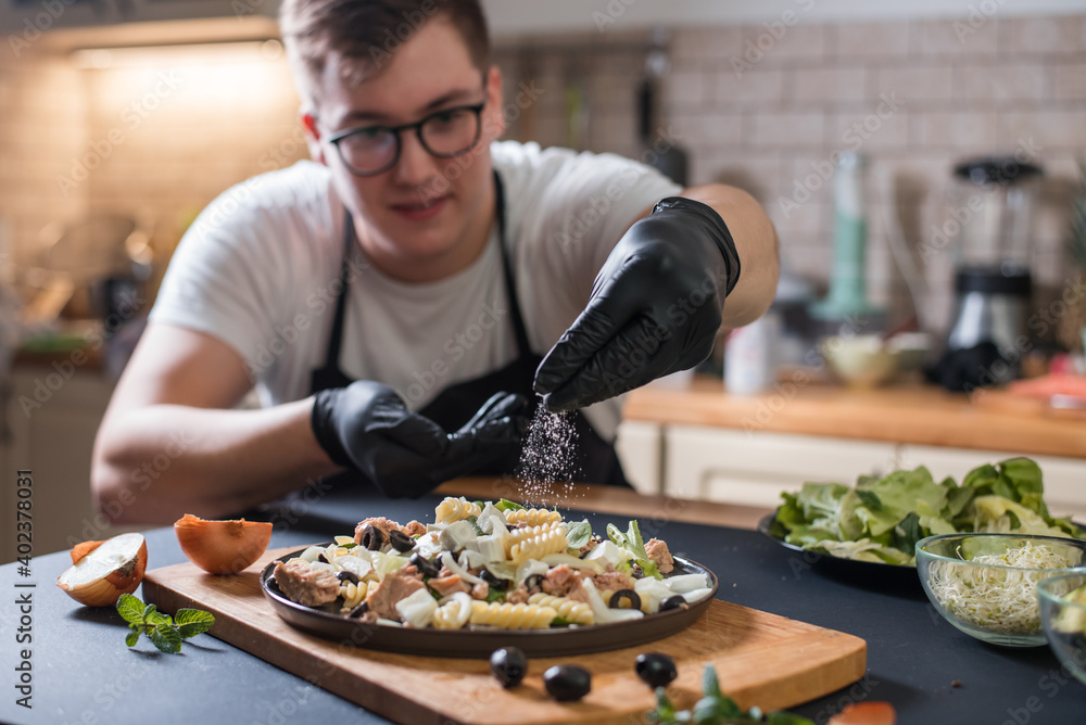 Male chef places finishing touches on meal Male chef places finishing touches on meal