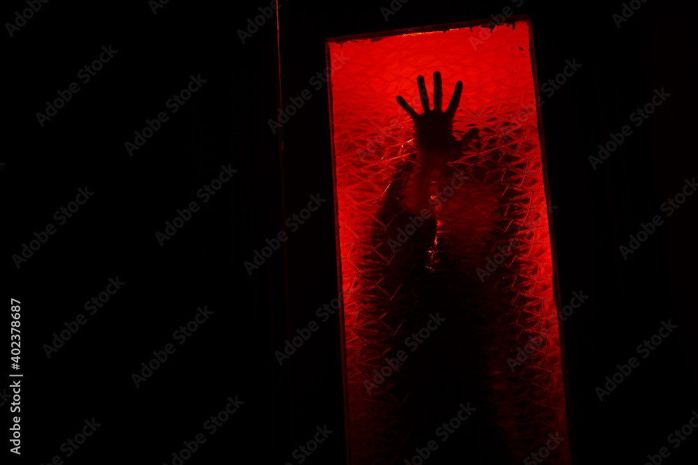 Fototapeta premium A hand in the dark behind the glass.