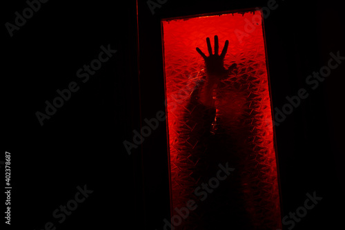 A hand in the dark behind the glass. photo