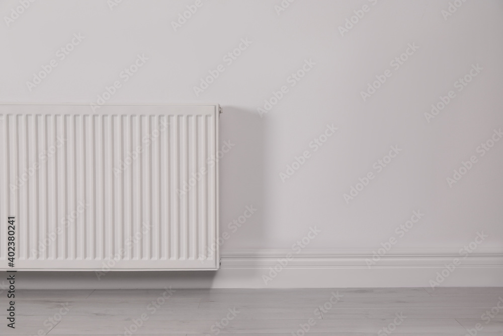 Modern radiator on white wall, space for text. Central heating system Modern radiator on white wall, space for text. Central heating system