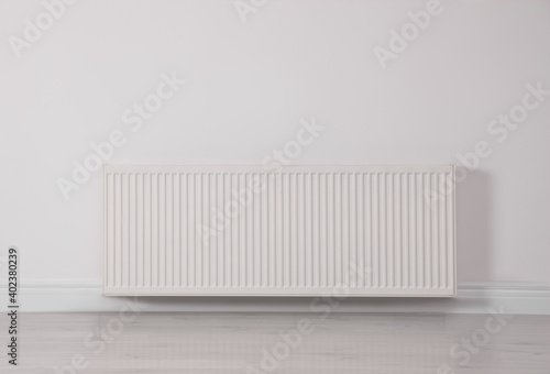 Modern radiator on white wall. Central heating system