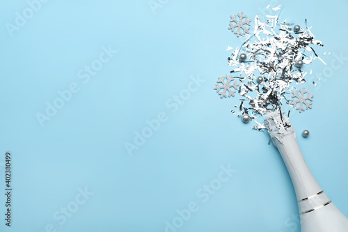 Flat lay composition with confetti and bottle of champagne on light blue background. Space for text