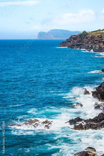 Seascape on Terceira island with waves on the rocks and Monte Brasil on the horizon, Azores PORTUGAL