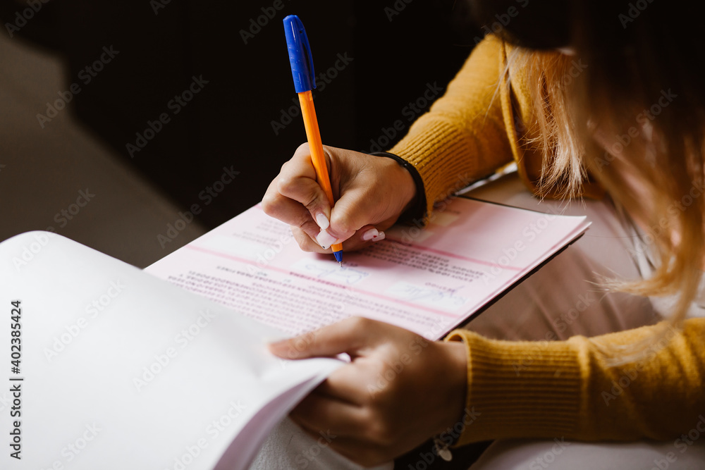 Fototapeta premium Latin woman hands writing and signing a document or a questionnaire in South America
