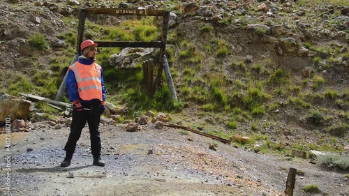 mining engineer, a geologist in the protective reflective vest, gloves and helmet, with hammer in hand.