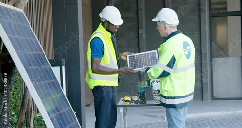 2 Electric solar panel industry engineers instructor and trainee teaching discussion with coworker teamwork about photovoltaic solarium electricity technology prototype business  