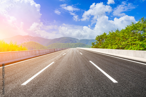 Asphalt road and green mountain under blue sky.Road and mountain background.