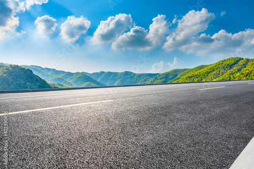 Asphalt road and green mountain under blue sky.Road and mountain background. © ABCDstock