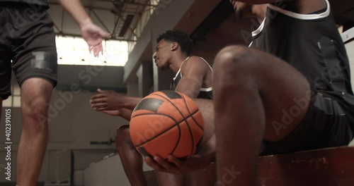 Basketball player walking by teammates sitting on a bench aplauding to him. Making high five photo