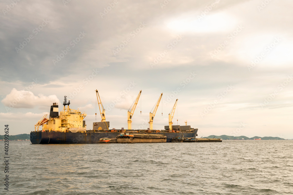 Large cargo ship for logistic import export goods anchor at sea in evening with golden sunset