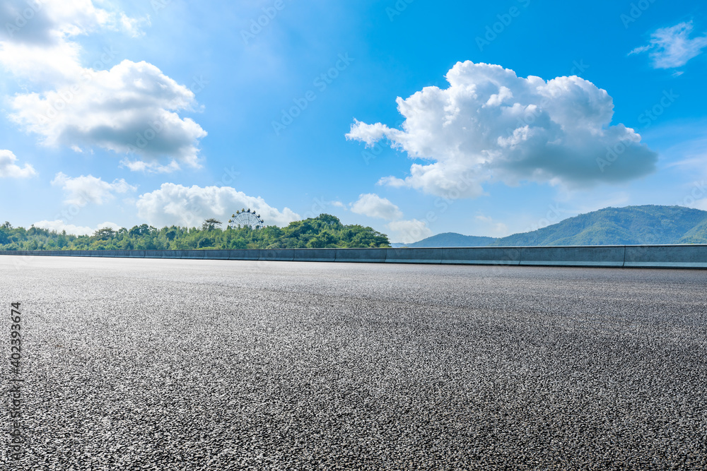 Fototapeta premium Asphalt road and green mountain under blue sky.Road and mountain background.