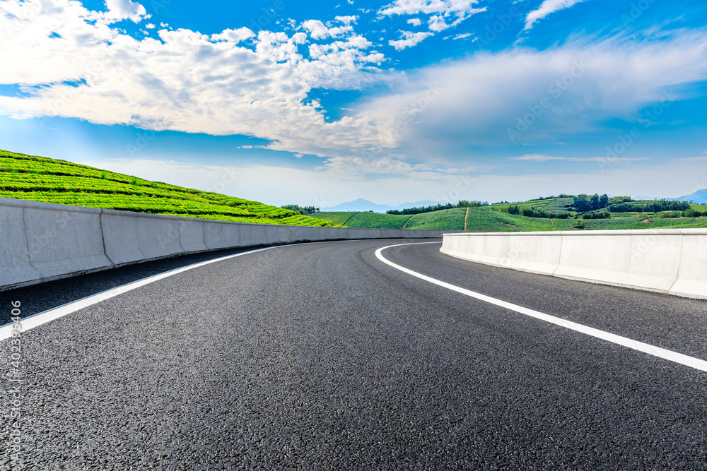 Asphalt road and mountain with tea plantation under blue sky.Road and mountain background. Asphalt road and mountain with tea plantation under blue sky.Road and mountain background.