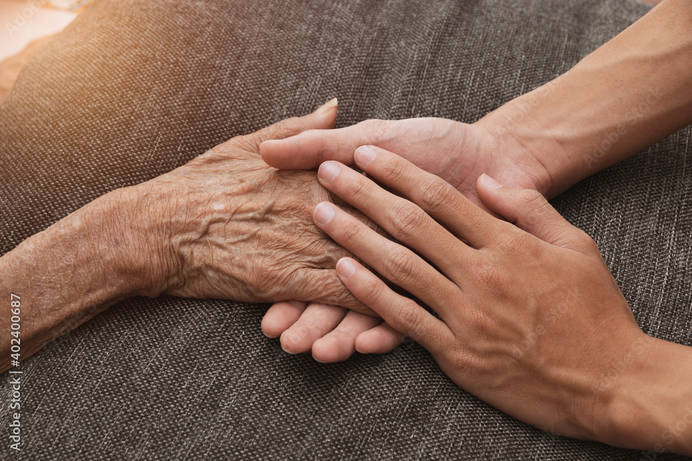 Fototapeta premium A person holding a hand An old woman lying in bed sick.