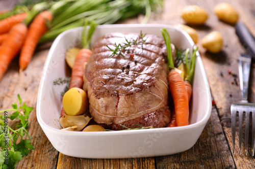 roast beef with vegetable on wood background