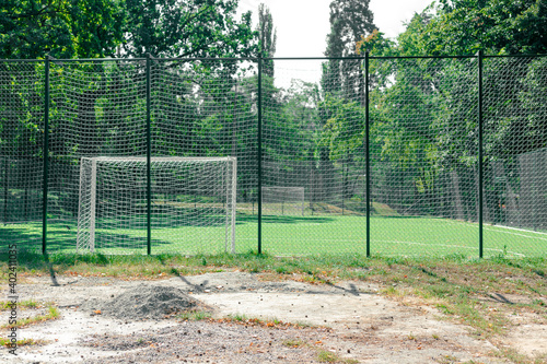 Soccer field behind the iron fence. Empty school soccer stadium