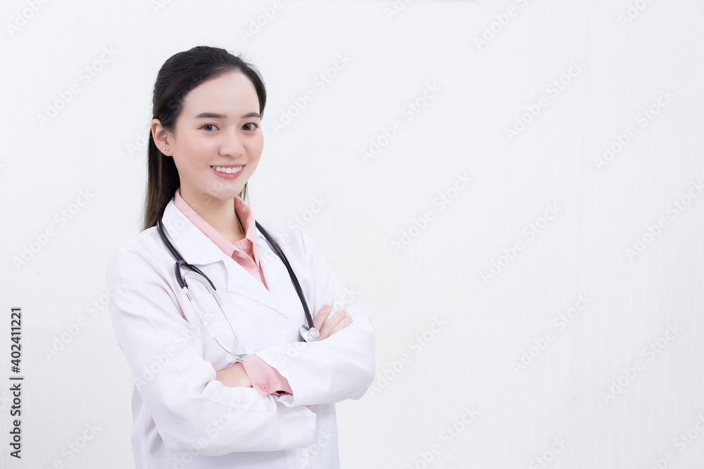 Asian woman doctor is arm crossing and smiling while she wears white lab coat.