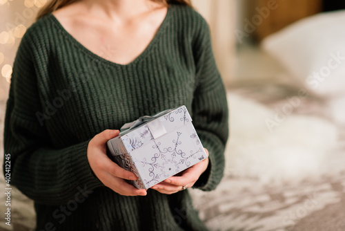 Beautiful young woman celebrating christmas at home, having fun while opening presents