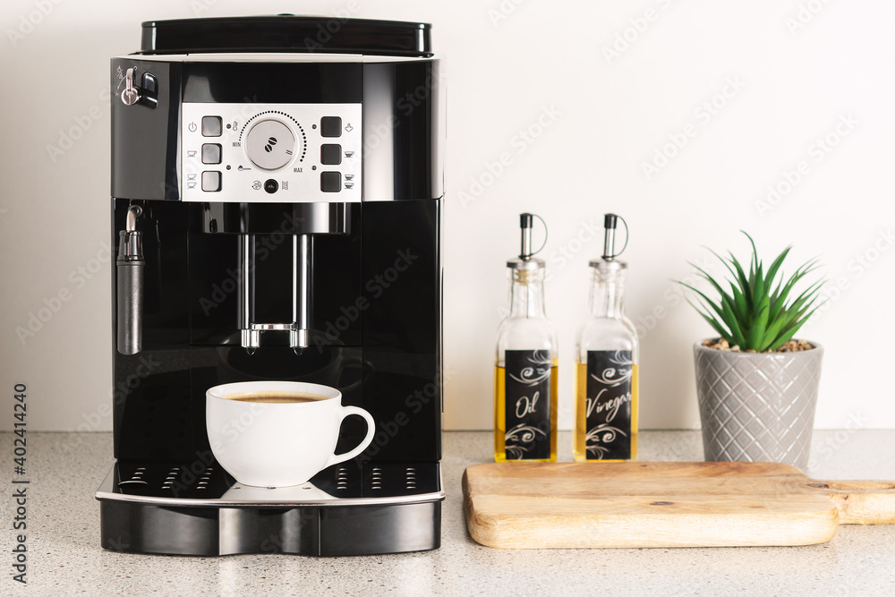 Modern espresso coffee machine with a cup in interior of kitchen closeup.  Stock Photo | Adobe Stock