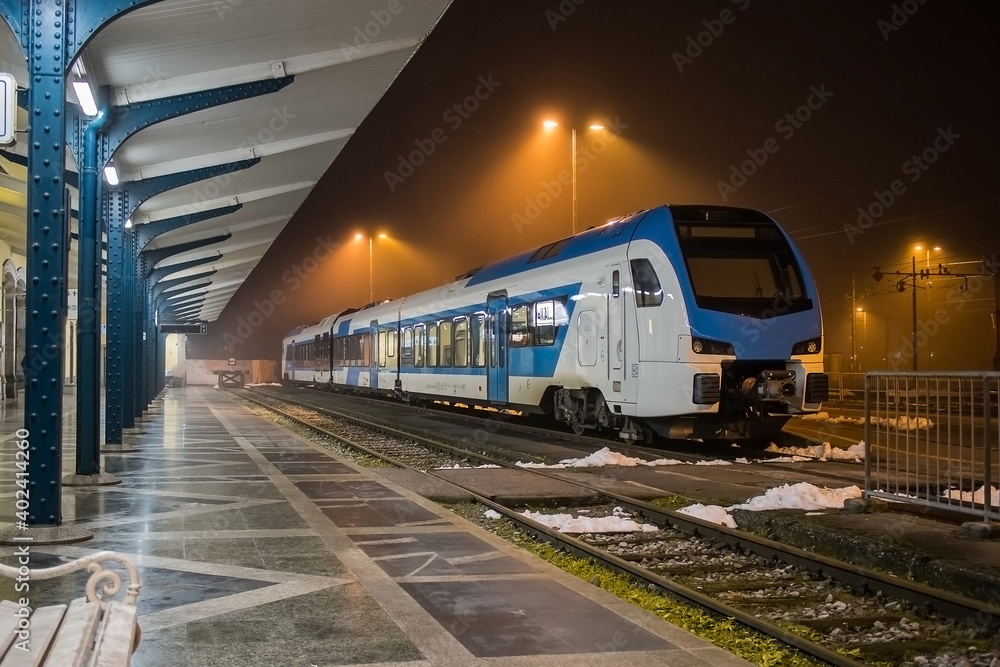 Naklejka premium Modern diesel passenger train is resting on a station platform in Ljubljana Slovenia during night time.,