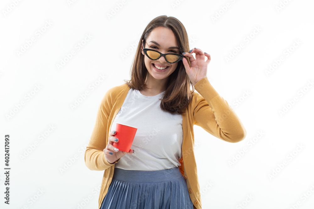 Young woman a yellow sweater drinks coffee from a red cup Young woman a yellow sweater drinks coffee from a red cup